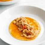Adding shredded chicken to the middle of corn tortilla