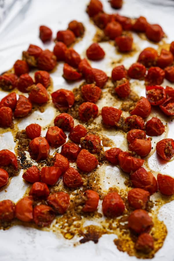 Roasted cherry tomatoes with garlic and olive oil on baking sheet