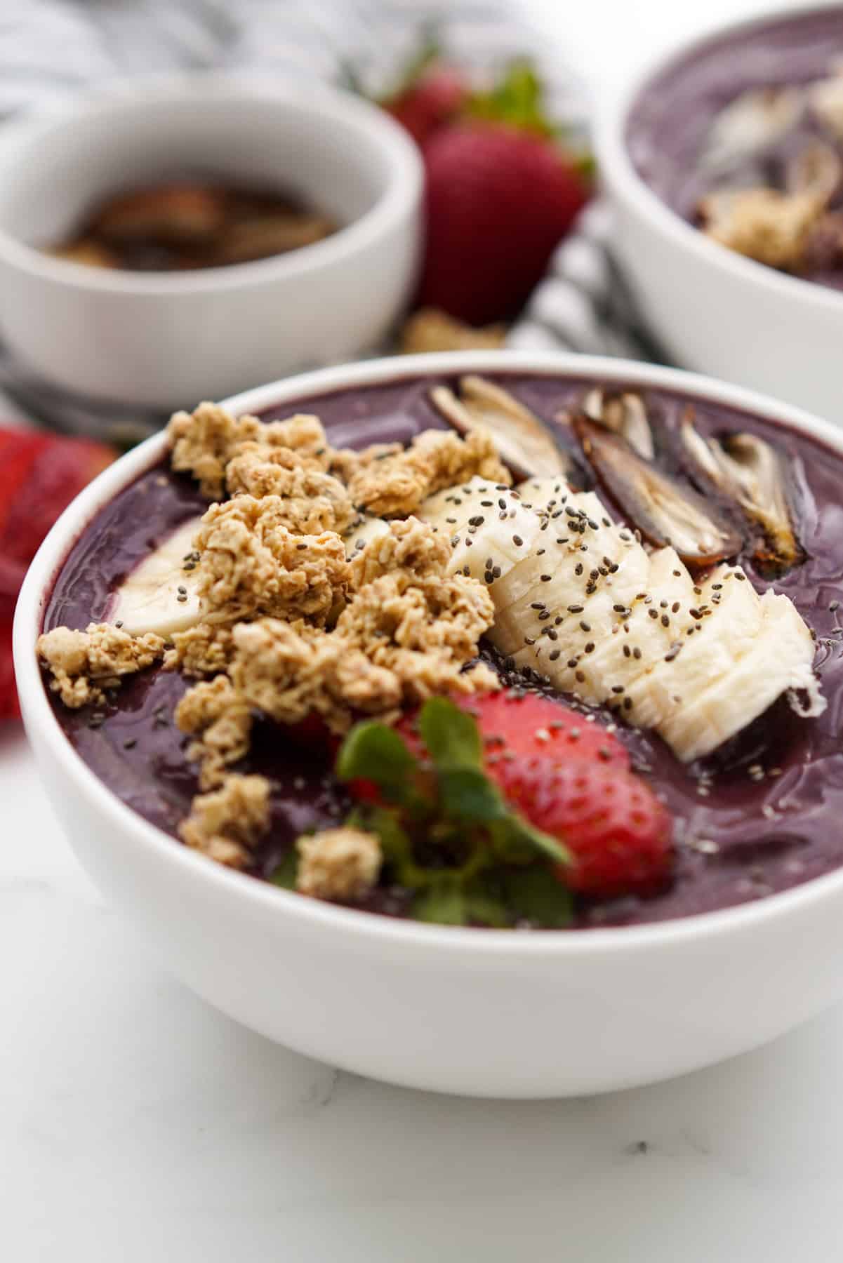 A bowl of acai smoothie bowl with bananas, strawberries, dates and granola