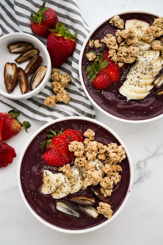 Two bowls of frozen acai smoothie bowl with toppings