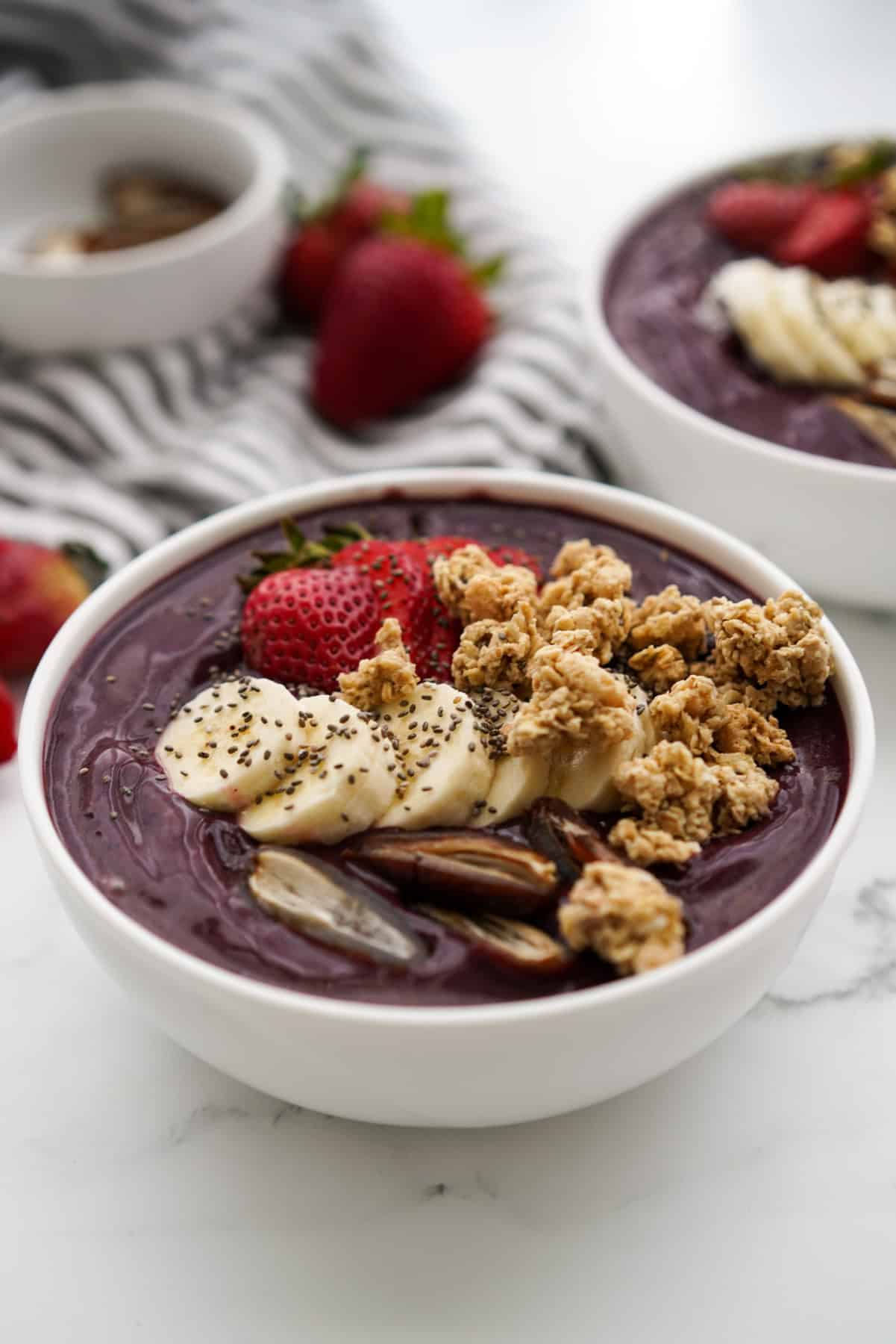 Frozen acai smoothie bowl topped with bananas, dates, granola and strawberries