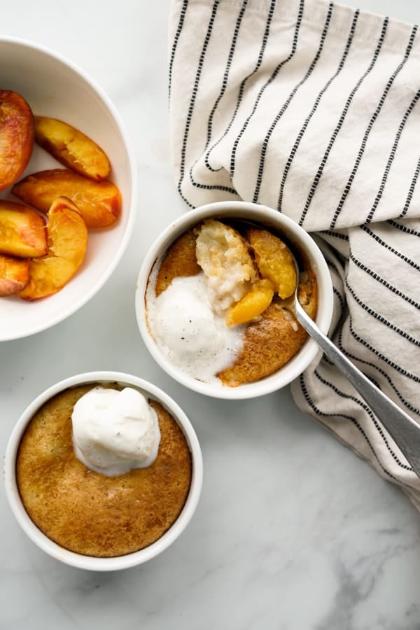 Two Ramekins of peach cobbler and a bowl of peaches 
