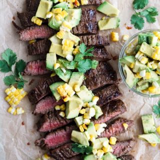 Sliced marinated flank steak topped with avocado corn pieces