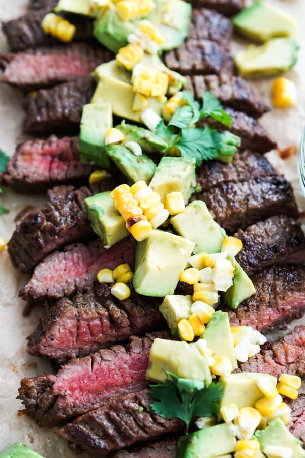 Closeup sliced steak with avocado and corn topping