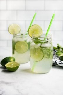 Two mason jar glasses of sparkling lime juice with lime
