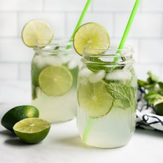 Two mason jar glasses of sparkling lime juice with lime