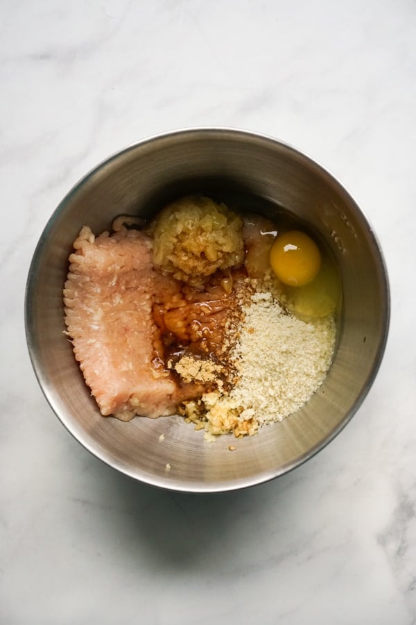 A large bowl filled with ground chicken, crushed pineapples, garlic, ginger, panko breadcrumbs, egg and other seasoning