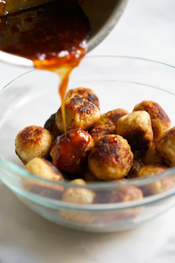 Pouring sweet and sour sauce onto chicken meatballs