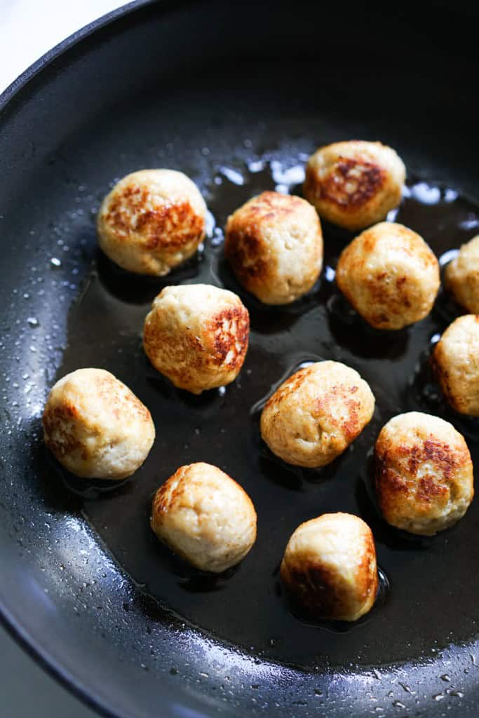 Pan frying chicken meatballs on a skillet