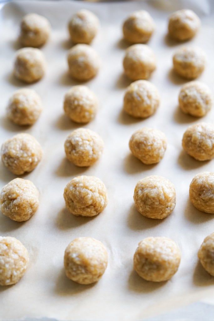 Raw chicken meatballs rolled into a ball on parchment paper.