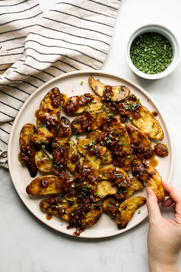 hand grabbing a fingerling potato from a plate