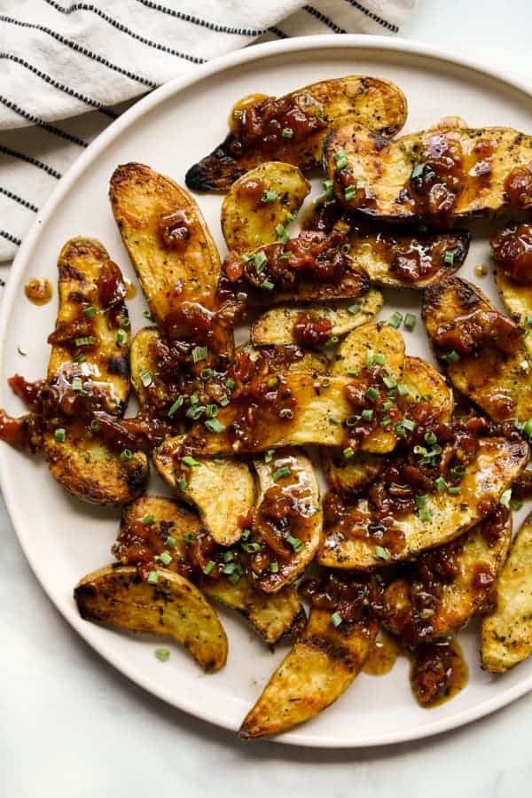 Closeup of a plate of Grilled fingerling potatoes topped with bacon vinaigrette