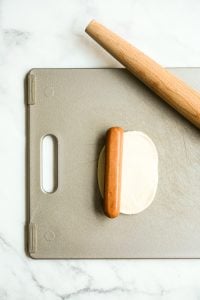 sausage placed on a rolled out dough on cutting board