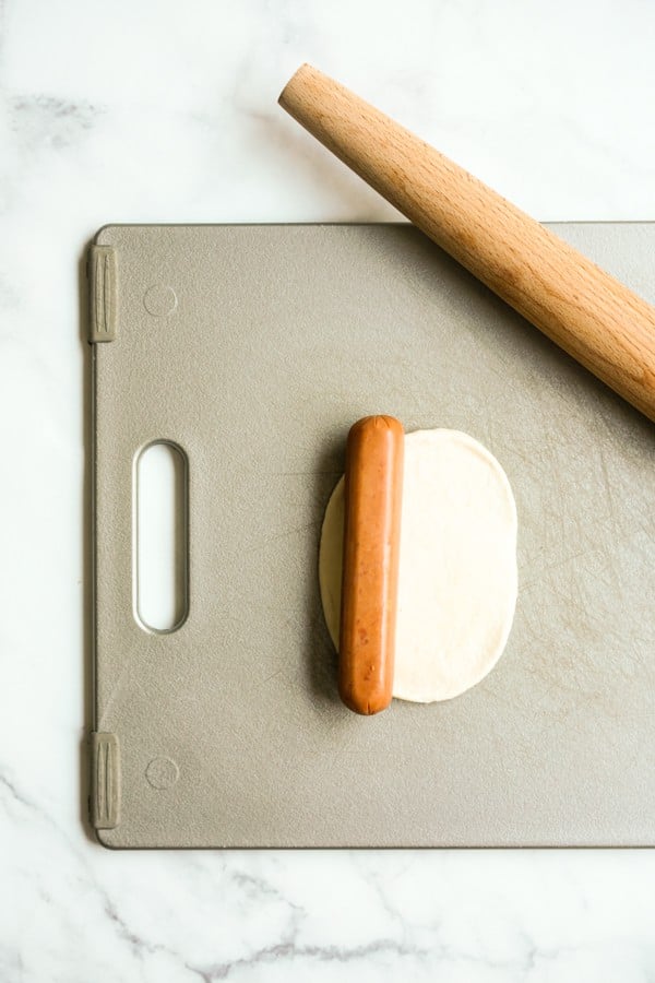 sausage placed on a rolled out dough on cutting board