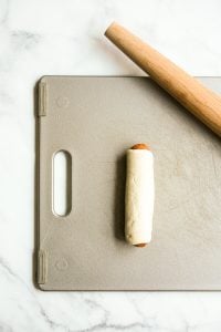 sausage rolled in dough on cutting board