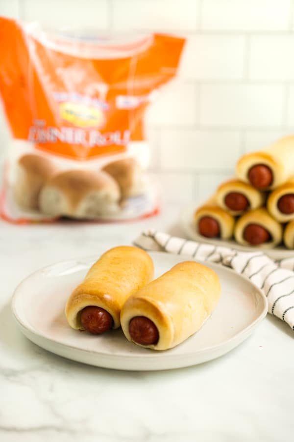 A plate of two Texas sausage rolls with a bag of Rhodes frozen dough in the background