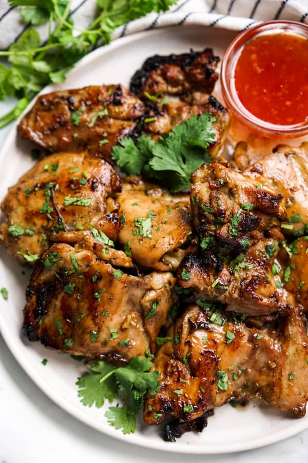 Closeup of Thai Grilled Chicken Thighs with a bowl of Thai Sweet Chili Sauce