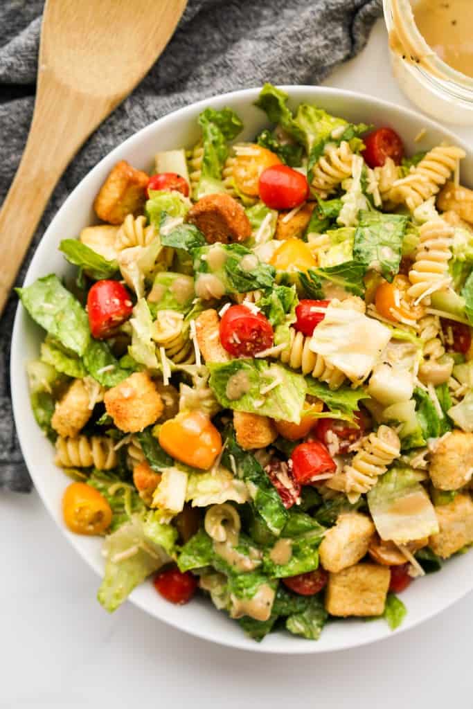 Top down view of a large serving bowl of caesar pasta salad tossed in homemade Caesar dressing