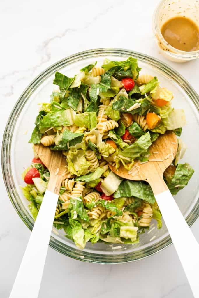 Tossing caesar pasta salad in dressing