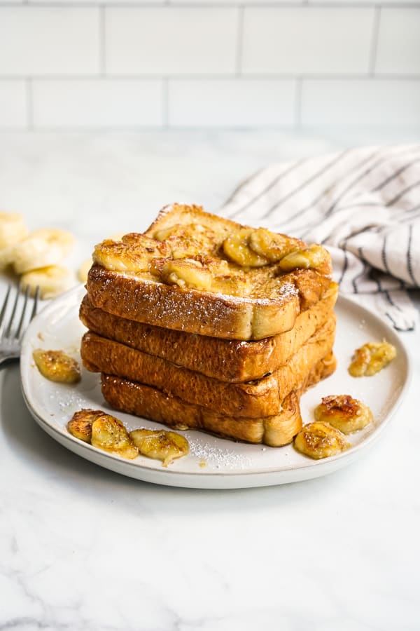 Caramelized banana french toast on a plate with slices of bananas around it