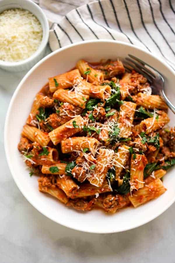 Closeup view of Creamy Tomato Pasta tossed with Italian sausage, spinach, parmesan and parsley