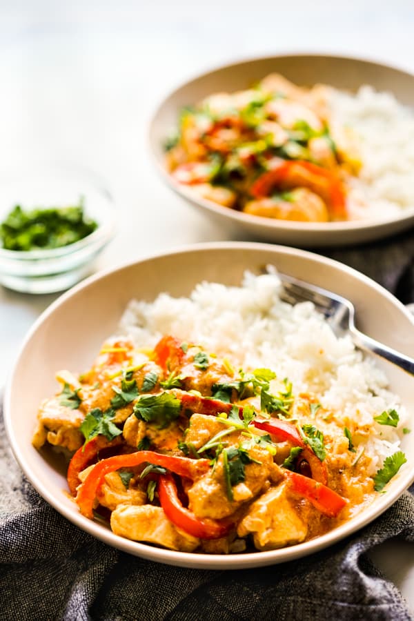 A bowl of rice with chicken curry, bell peppers and zucchini