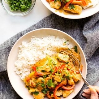 Two bowls of Thai Red Curry with Chicken on rice, with a fork digging into one of them