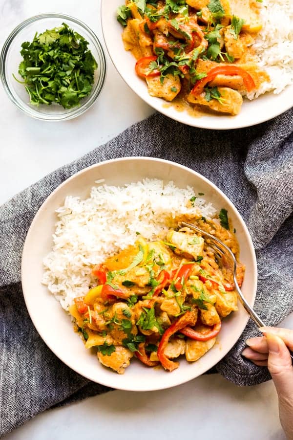 Two bowls of Thai Red Curry with Chicken on rice, with a fork digging into one of them