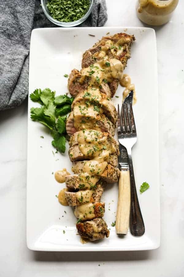 Sliced pork tenderloin on a rectangular plate topped with cream gravy