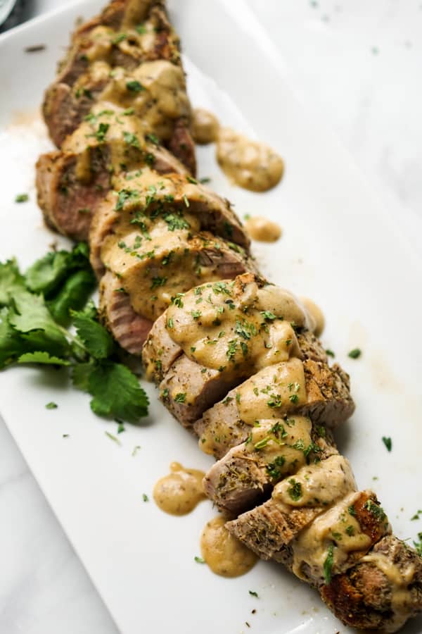 A plate of sliced roasted pork tenderloin topped with cream gravy