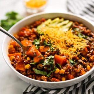 Spoon digging into a bowl of Turkey Sweet Potato Chili with garnishes