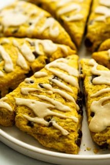 A plate of pumpkin scones with chocolate chips and icing