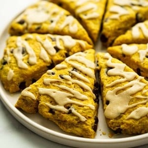 A plate of pumpkin scones with chocolate chips and icing