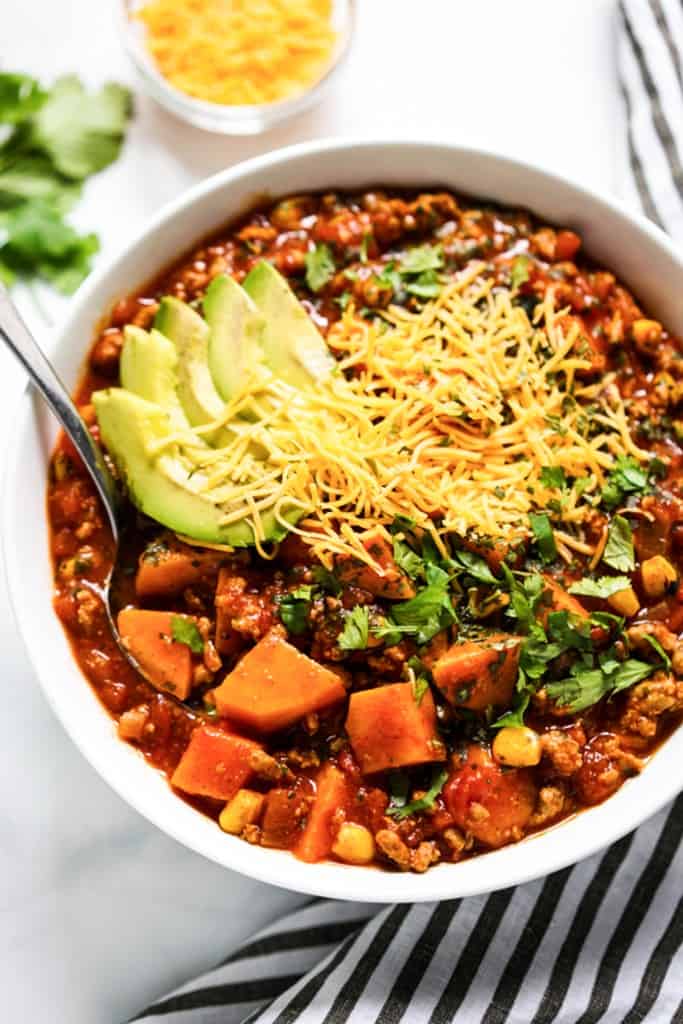 Using a spoon to scoop out some chili from a bowl