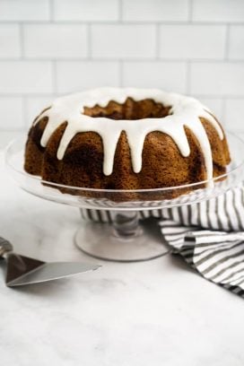 Cinnamon swirl bundt cake drizzled with icing on a cake stand