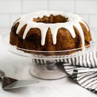 Cinnamon swirl bundt cake drizzled with icing on a cake stand