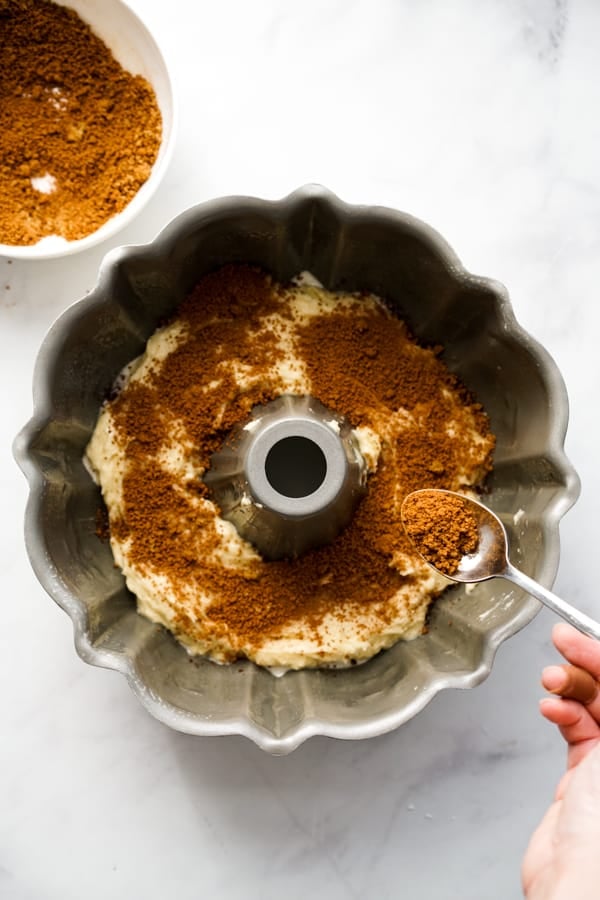 Adding cinnamon mixture to cake mixture in bundt pan