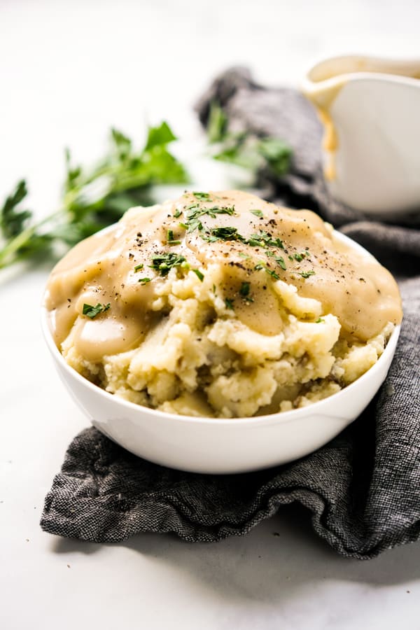 A bowl of potatoes with brown gravy on top