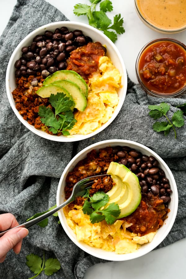 Using a fork to dig into a bowl of Mexican Breakfast Bowl.