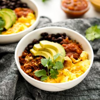 Breakfast bowl filled with migas, chorizo, avocado, beans, and salsa