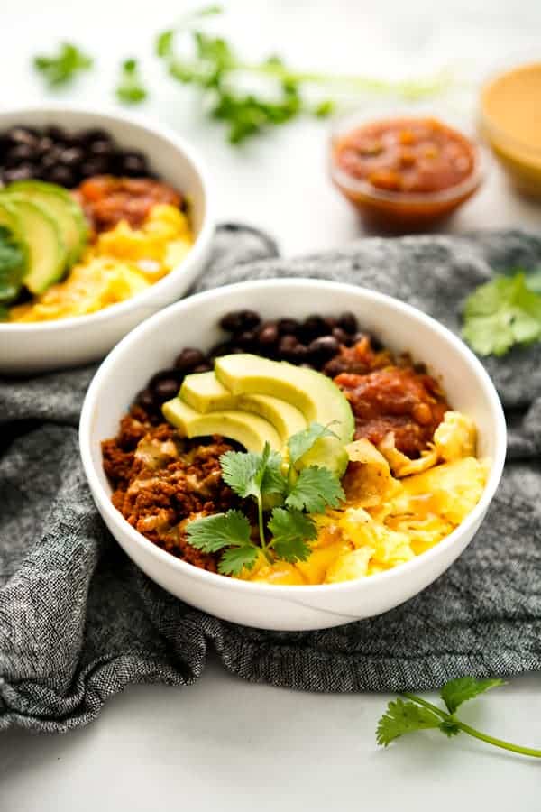 Breakfast bowl filled with migas, chorizo, avocado, beans, and salsa