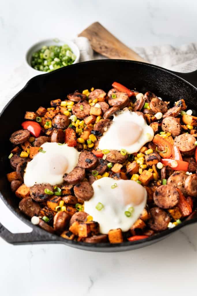 A skillet of sweet potato and sausage hash with overeasy egg on top