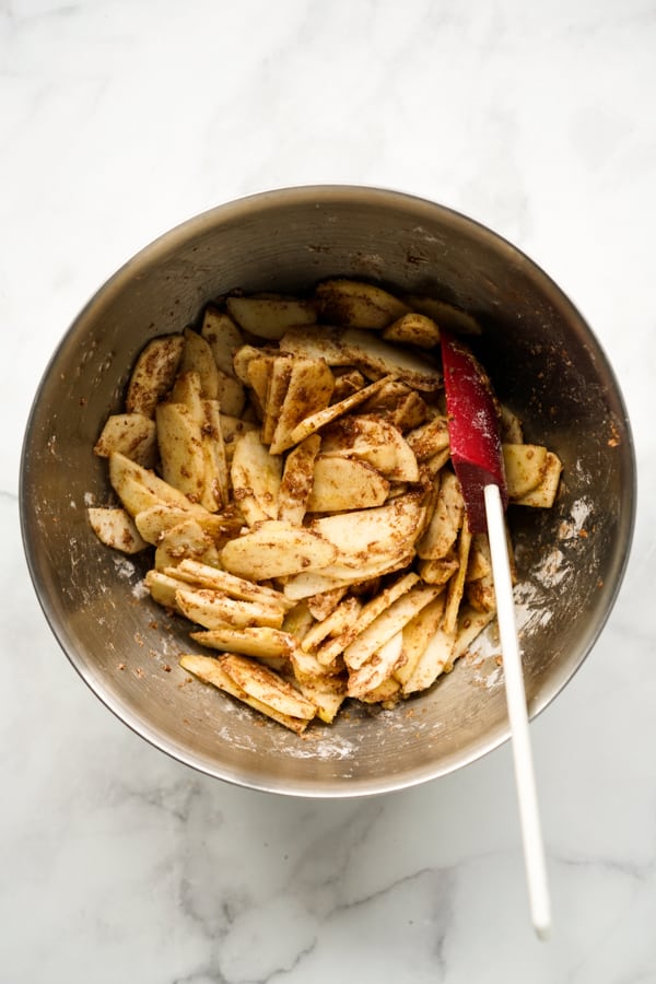 A bowl of sliced apples combined with cinnamon and brown sugar