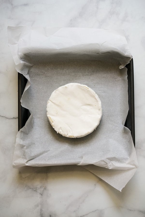 Brie placed on a baking dish lined with parchment paper
