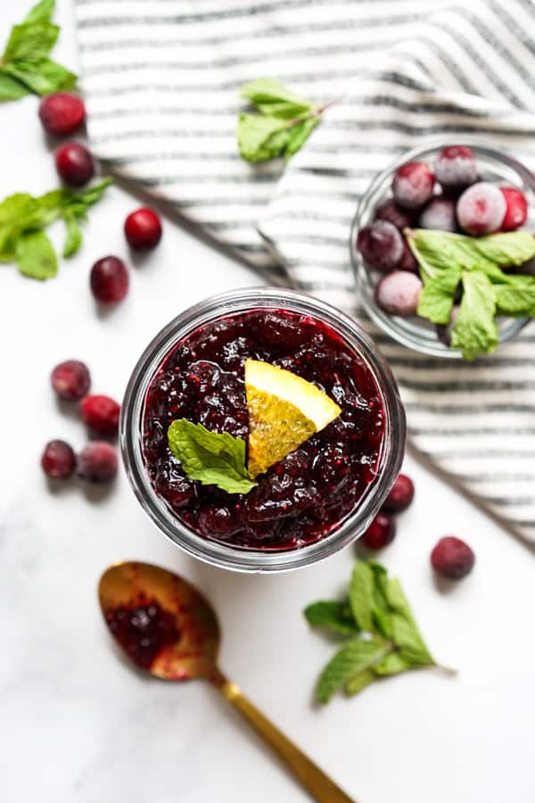 top down view of a bowl of cranberry sauce with fresh cranberries scattered all over the side