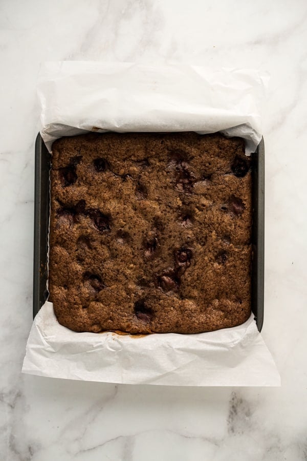 Brownie in baking dish lined with parchment paper after baking