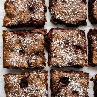 Six square pieces of chocolate brownies loaded with cherries, topped with powdered sugar