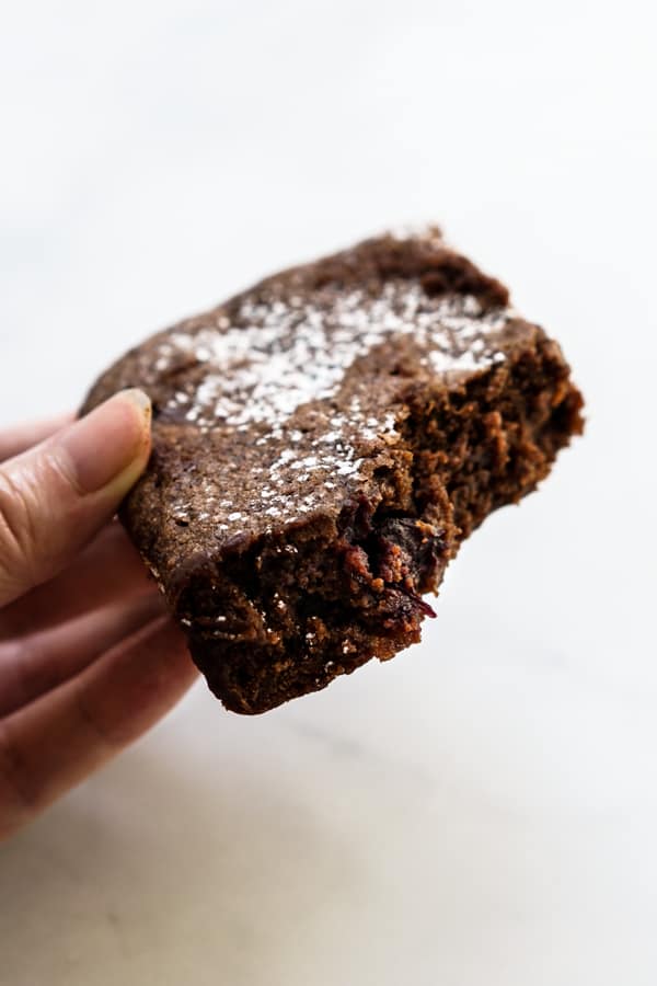 Hand holding a piece of chocolate cherry brownie