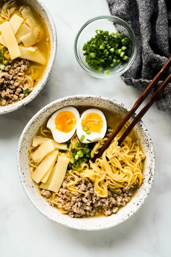 Top down view of a bowl of noodle soup with chopsticks in it