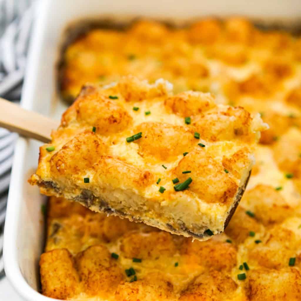 Lifting up a piece of sausage Tater tot breakfast casserole